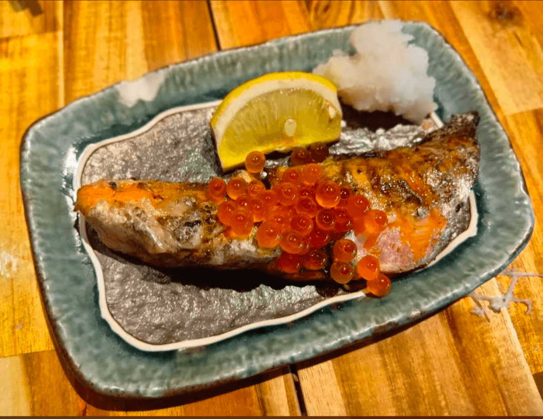 Grilled salmon topped with salmon roe, served with a lemon wedge and grated daikon.